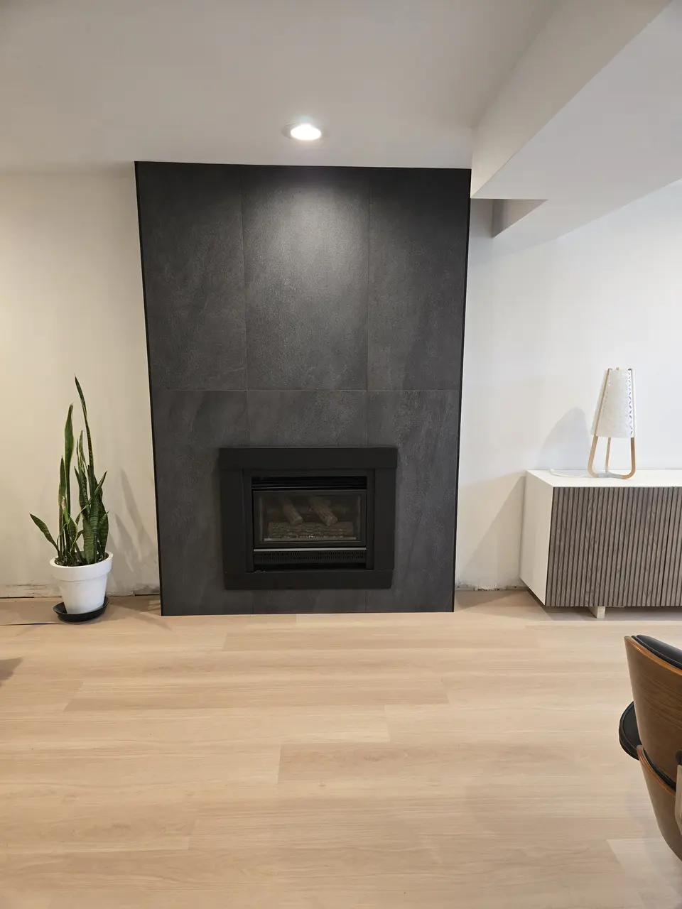 Finished basement family room with new flooring and a modern fireplace wall