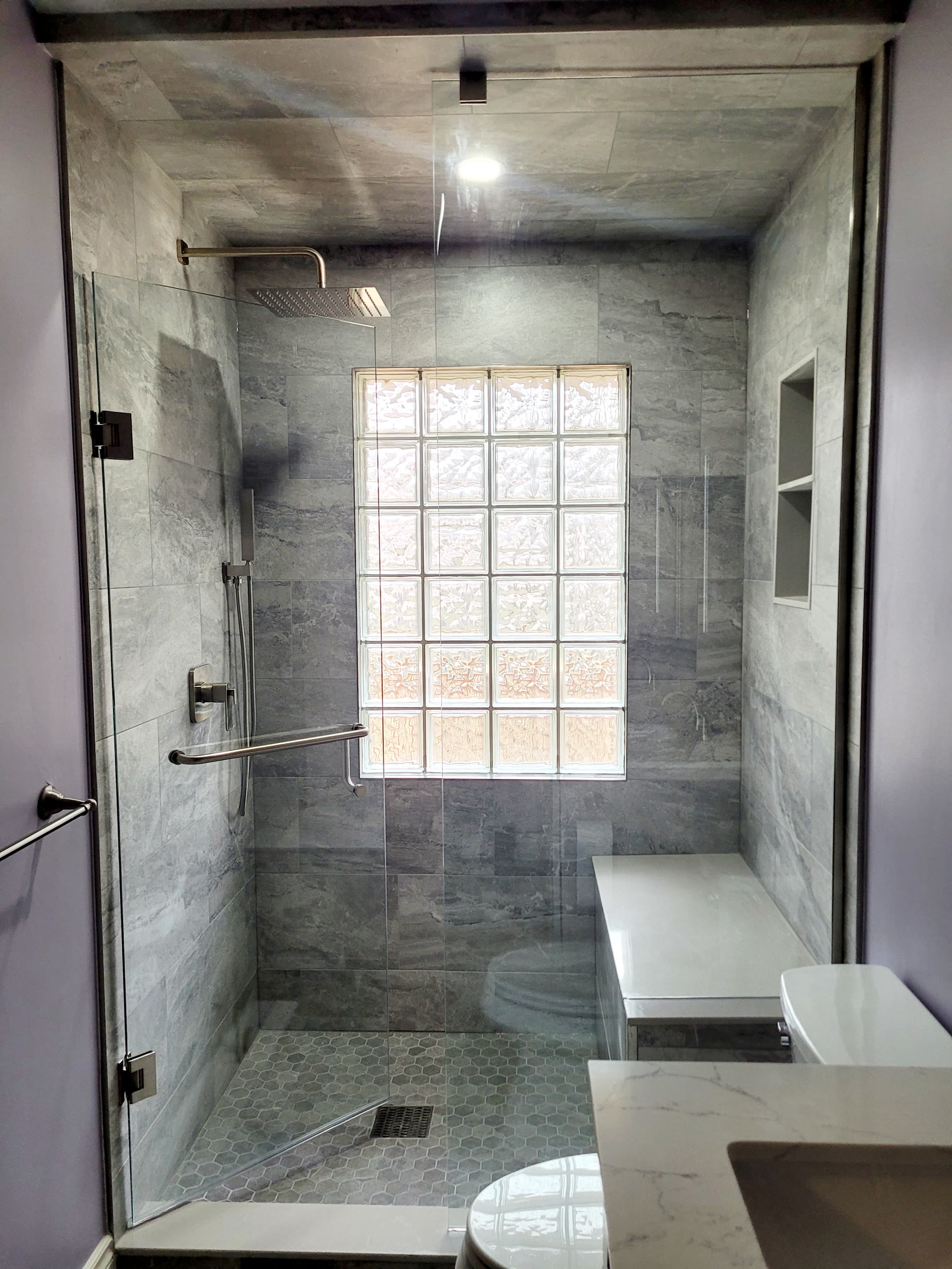 Glass shower with tiled walls, bench, niche and glass-block window