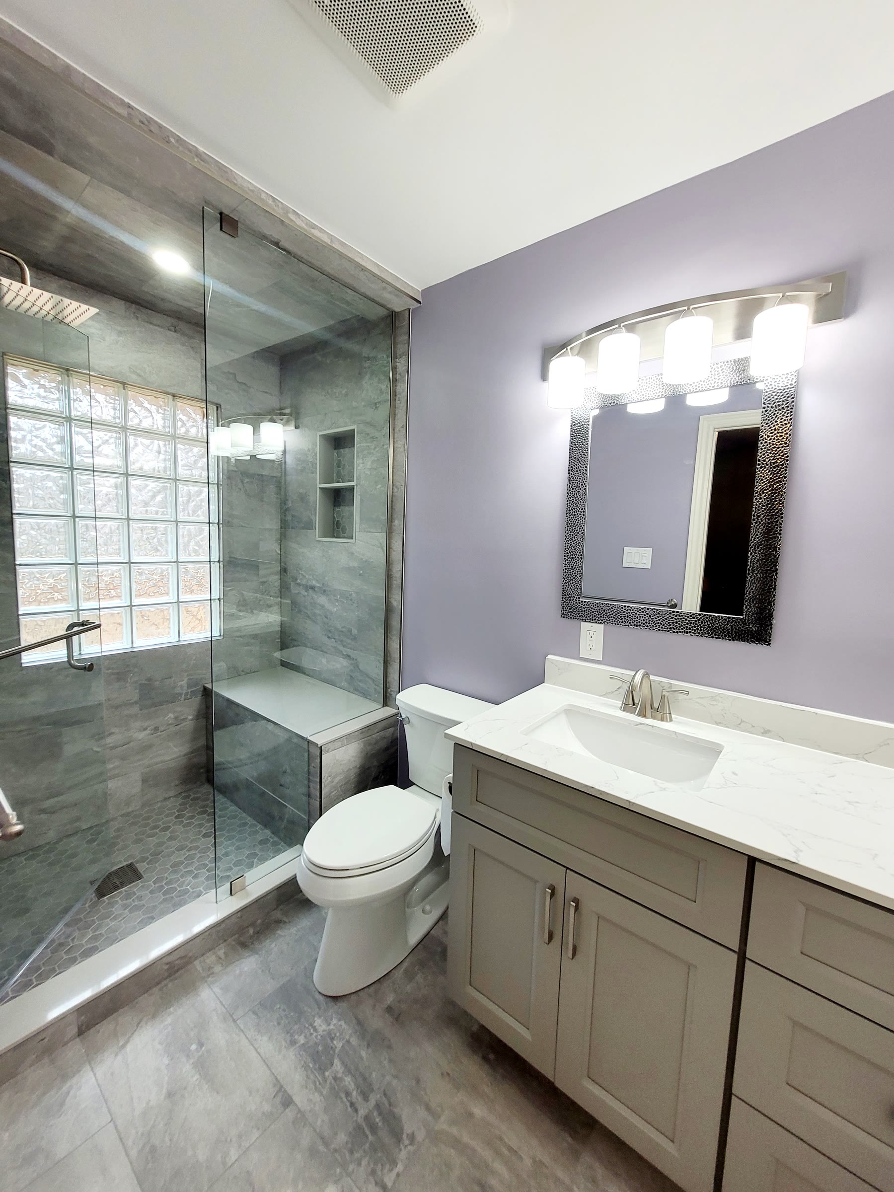Finished bathroom with glass shower, tiled walls and double vanity