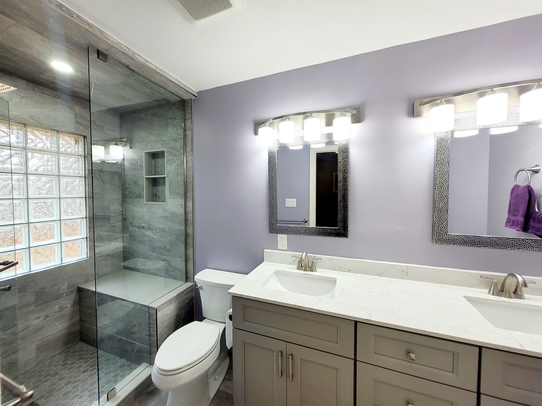 Double vanity with stone counter, two mirrors and coordinated lighting
