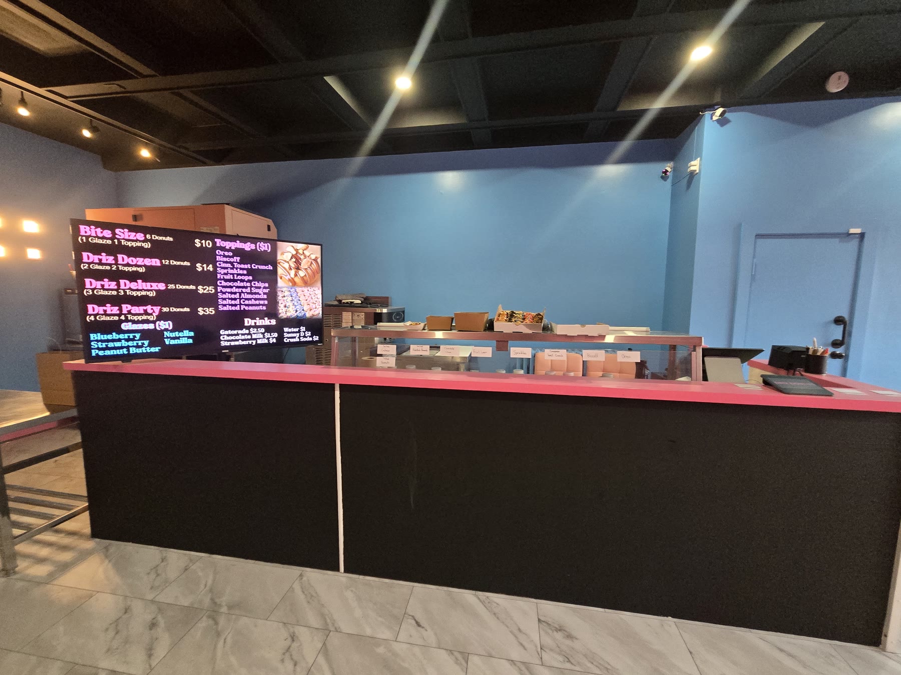 Long black commercial counter with illuminated menu boards and blue feature wall