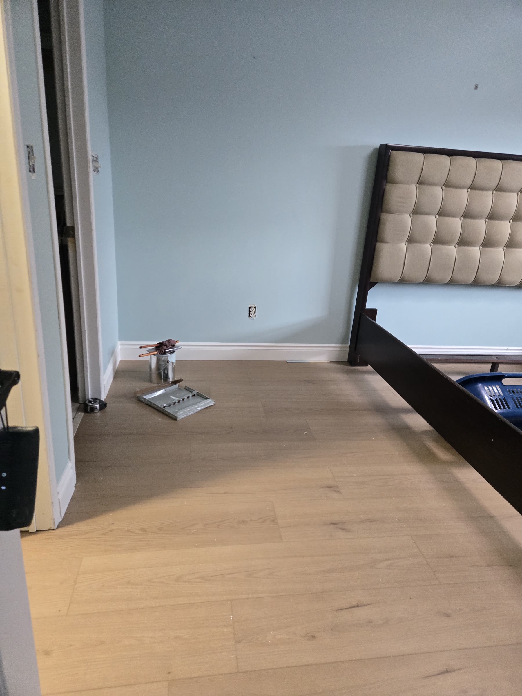 Bedroom with light floor, blue-grey walls and completed white baseboards