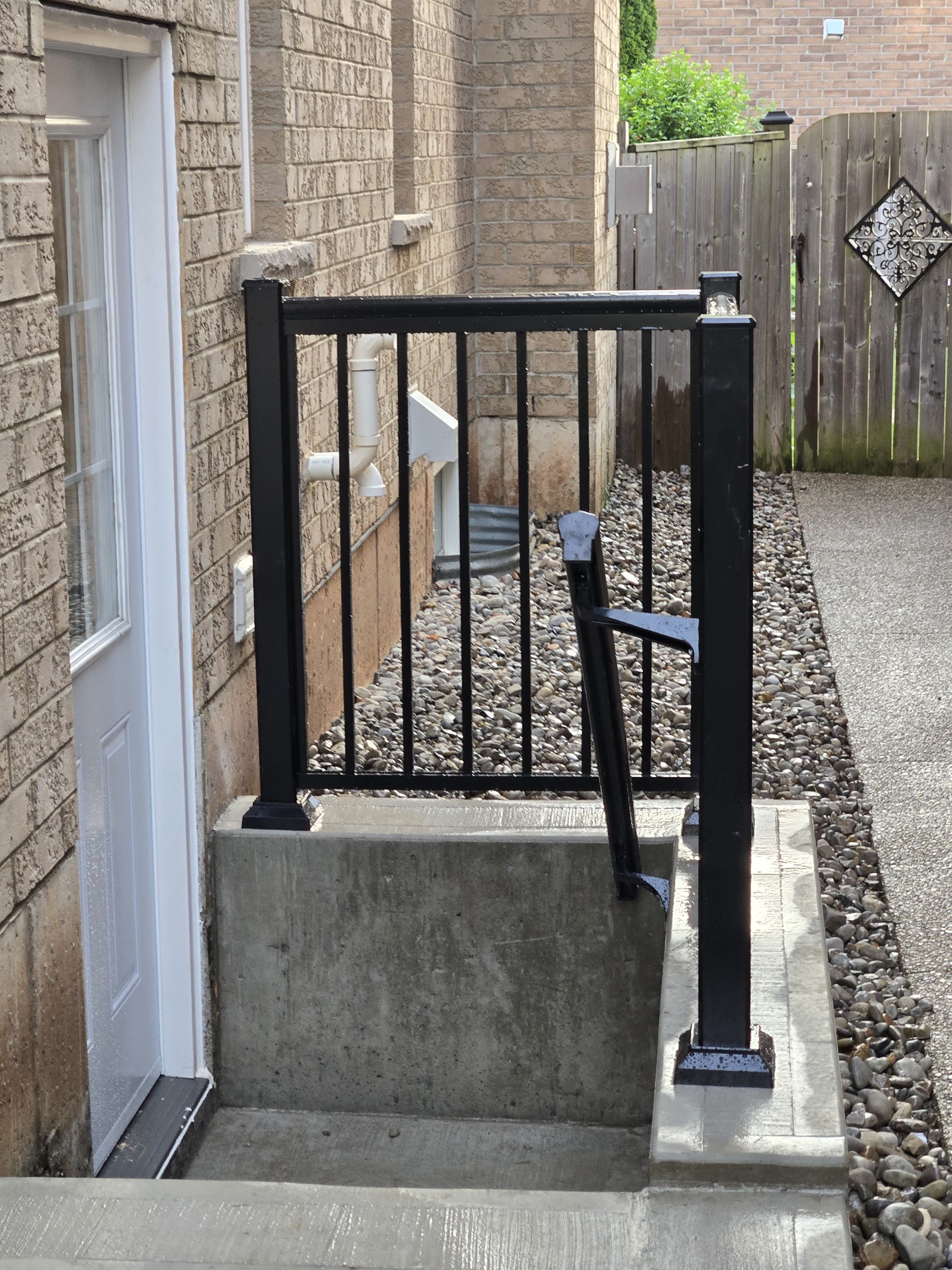 Finished concrete basement stairwell and black metal railing beside the house